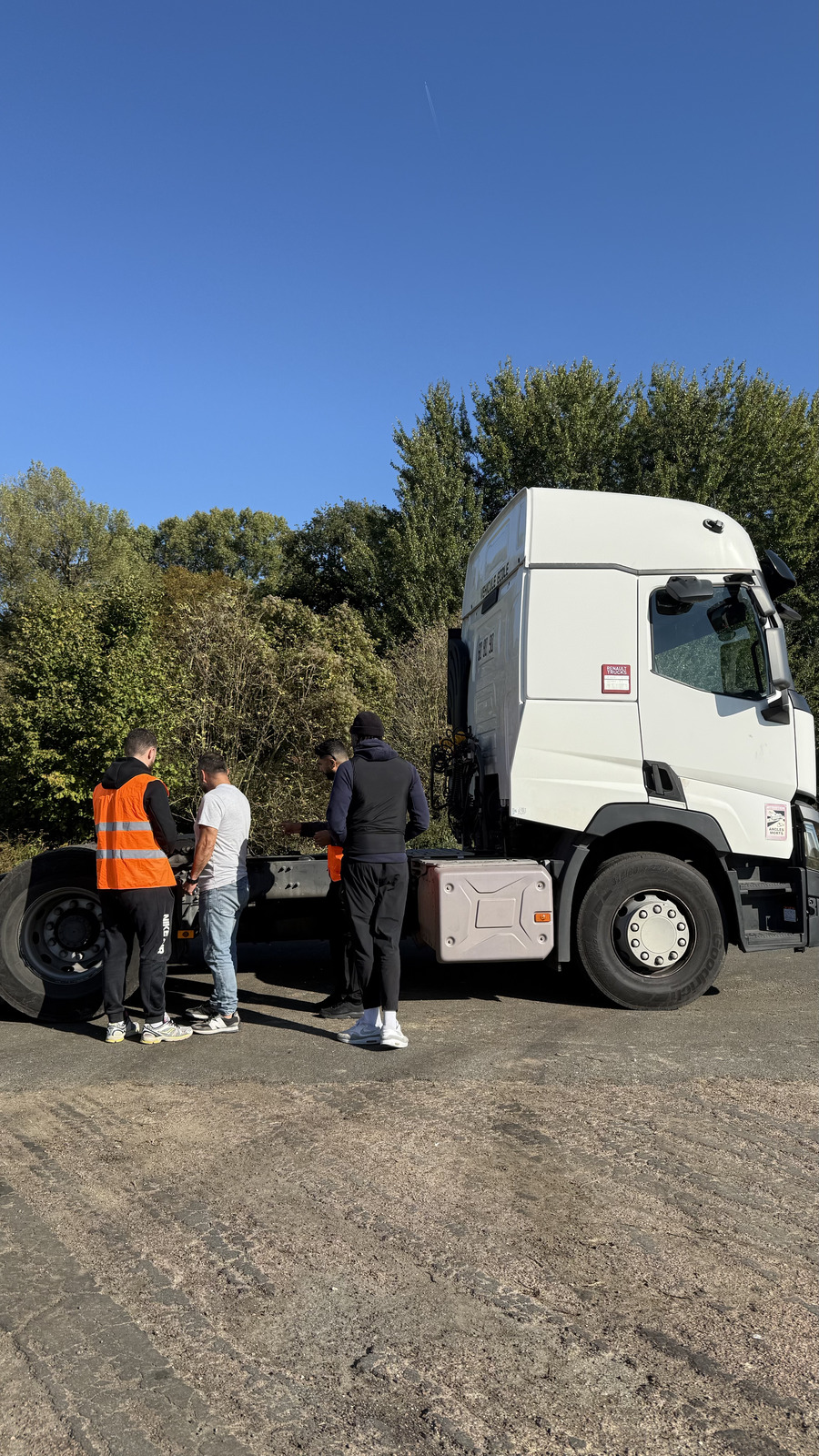 Apprenants et formateur en gilet orange réalisant le contrôle d'un poids lourd